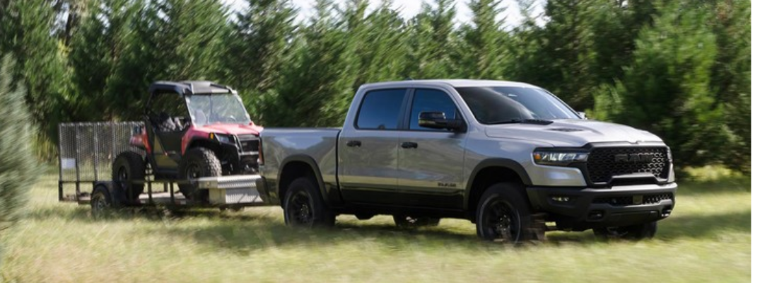 2026 Ram 1500 towing an ATV while driving on grass